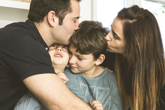 Portrait of a happy family kissing and hugging at home. Family lifestyle showing affection