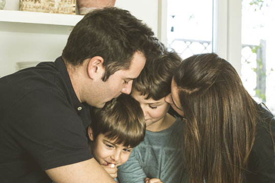 Portrait of a happy family kissing and hugging at home. Family lifestyle showing affection