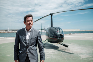 Businessman standing near private helicopter