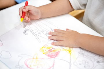 little girl plays and learns to coloring Crayon on the paper in the ice-cream restaurant., Bangkok, Thailand.