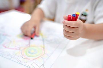 little girl plays and learns to coloring Crayon on the paper in the ice-cream restaurant., Bangkok, Thailand.