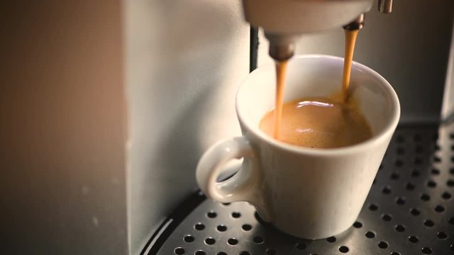 espresso runs, is dripping, pouring in a white cup from an espresso machine