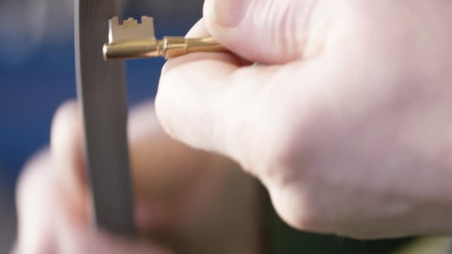 Locksmith filing the edges of a new duplicate key after cutting it, in slow motion