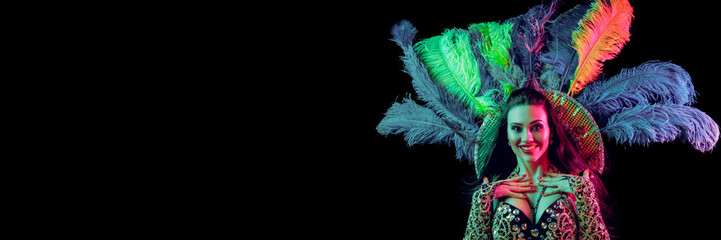 Beautiful young woman in carnival peacock costume. Beauty model woman at party over holiday background with magic glow. Christmas and New Year celebration. Glamour lady with perfect make up and