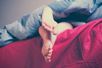 Sleep and relax concept. Close up feet of a girl lying in bed.