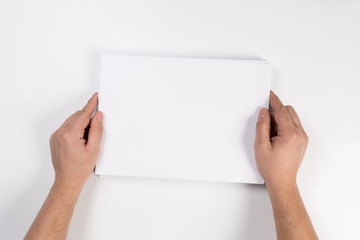 Hand holding white blank paper sheet mockup, isolated. Arm in shirt hold clear brochure template...