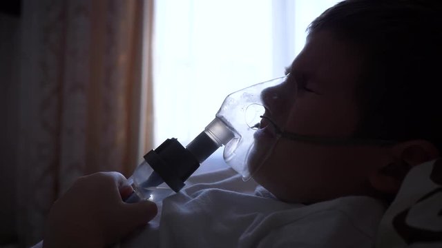 nebulizer procedure, aching child boy in mask breathes through inhaler with medication for Preventing asthma at hospital