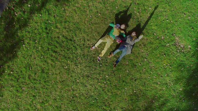 Aerial view of family laying down on grass at public playground, Zagreb.