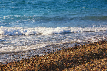 Waves on pebble beach on calm sunny day. Montenegro, Adriatic Sea