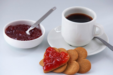 cup of coffee with heart-shaped cookies and strawberry jam