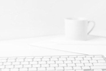 White cup of freshly brewed coffee tea computer keyboard notes on monochrome monotone background....