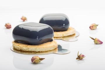 French mousse cakes on cookies covered with dark glaze on white background