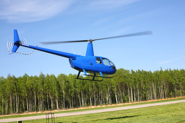 The aircraft - Blue small helicopter makes flight low height.