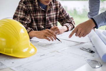 Construction engineering or architect discuss a blueprint while checking information on drawing and sketching meeting for architectural project in work site