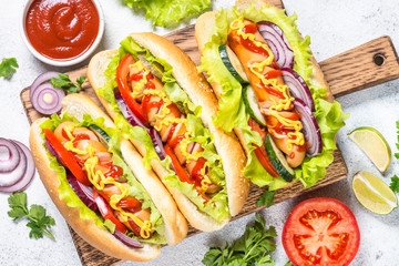 Hot dog with fresh vegetables on white top view.