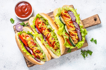 Hot dog with fresh vegetables on white top view.