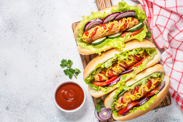 Hot dog with fresh vegetables on white top view.