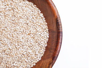 Raw barley grain in wooden bowl. Food round container isolated on white in studio.