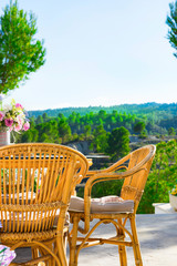 Terrace of luxurious white villa with wicker chairs table flowers bouquet on table fascinating view of valley mountains covered with green trees. Sunny day. Vacation holiday escape tranquility