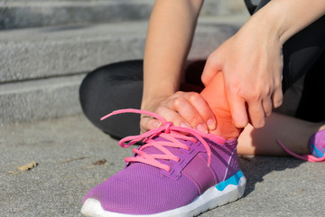 Ankle pain caused by exercise. Women who are sitting and use the handle on the ankle from the pain.
