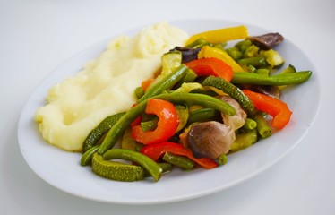 Mashed potatoes and vegetables with mushrooms on a white plate.