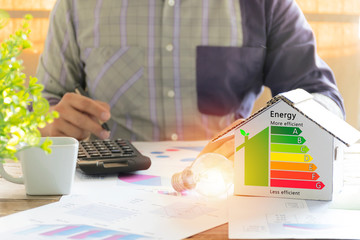Men who are calculating cost savings from energy. Hand holding a pen.