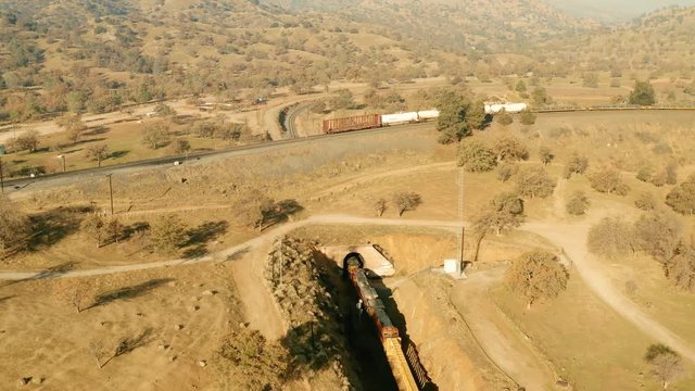 The aerial camera follows directly over the locomotives as they enter the eastern loop tunnel at 150 feet AGL. The camera descends, the train exits the tunnel into a clockwise turn going to the west.