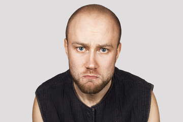 portrait of a bald upset offended man experiencing stress due to problems on gray background