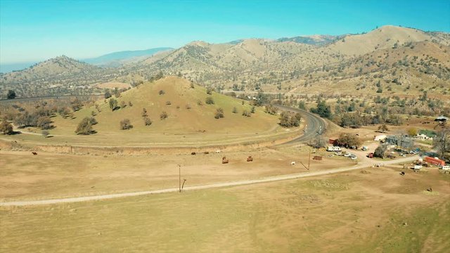 The aerial camera flies from the south toward the rail loop then rotates to the left and the locomotives come out of the northern lower tunnel in the Tehachapi Railroad Loop.