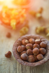 Close up view photo composition of just harvested whole hazelnuts with shells in a plate of dried leaves on the rustic wooden board. Selective focus. Toned