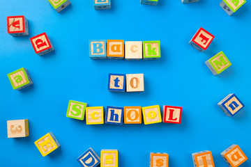 Back to school. Wooden colorful alphabet blocks on blue background, flat lay, top view.