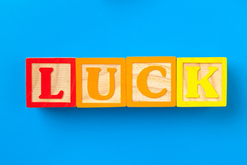 Luck. Wooden colorful alphabet blocks on blue background, flat lay, top view.