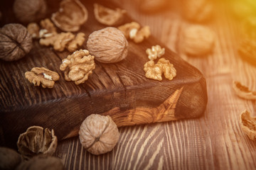 Close up view composition of walnut kernels and whole walnuts on rustic cuting desk. Selective focus. toned