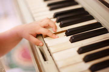 Fototapeta premium the child's hand plays the piano keys. Close up