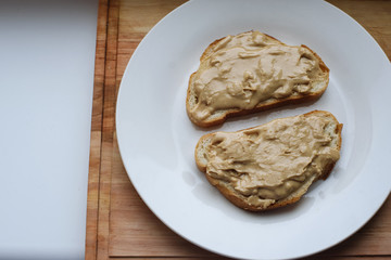 Delicious peanut butter sandwich breakfast on white plate, wooden table background. Sweet food, breakfast concept