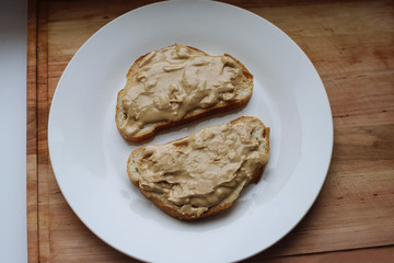 Delicious peanut butter sandwich breakfast on white plate, wooden table background. Sweet food, breakfast concept