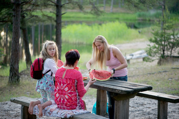  happy family eats watermelon at the lake