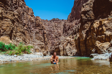 Young adventurous man in Wadi Zarqa Ma'in canyon located in the mountainous landscape to the east of the Dead Sea, near to Wadi Mujib, Jordan, Middle East