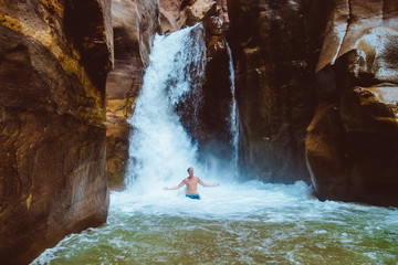 Man relaxing under waterfall, Jorda. wadi mujib