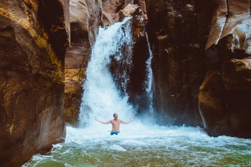 Fototapeta na wymiar Man relaxing under waterfall, Jorda. wadi mujib