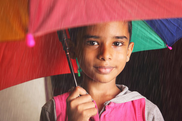 Indian little boy posing to camera with umbrella in rainy day