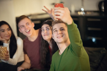 Young friends sitting on the sofa and young man taking a selfie