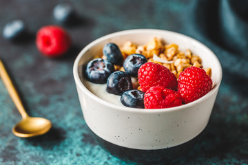 Vegetarian breakfast, a bowl with organic granola, fresh raspberries and blueberries and coconut yoghurt.