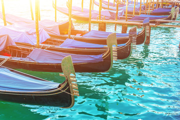 A number of gondolas at the pier in the water, boat parking. Venice Postcard Concept.