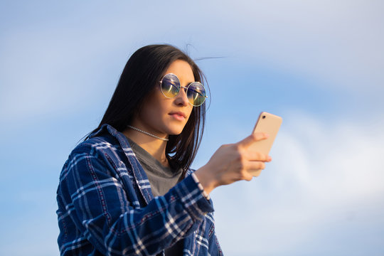 Brunette girl wearing sunglasses on her phone