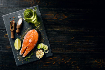 salmon steak prepared for frying with ingredients on a dark background