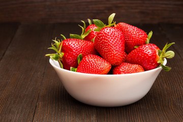 Fresh ripe strawberries in a simple white bowl