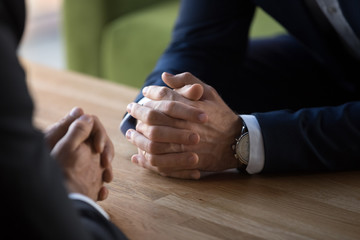 Clasped male hands of two businessmen negotiate at table, hr recruiter making hiring decision at difficult job interview, opponents dialogue debate, business confrontation challenge concept, close up - obrazy, fototapety, plakaty