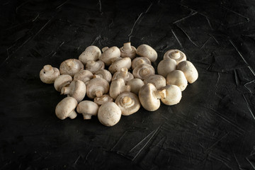 Fresh champignon mushrooms on a dark background. Top view