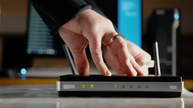 A man connects the ethernet cables to the WAN port and LAN ports of the WiFi router